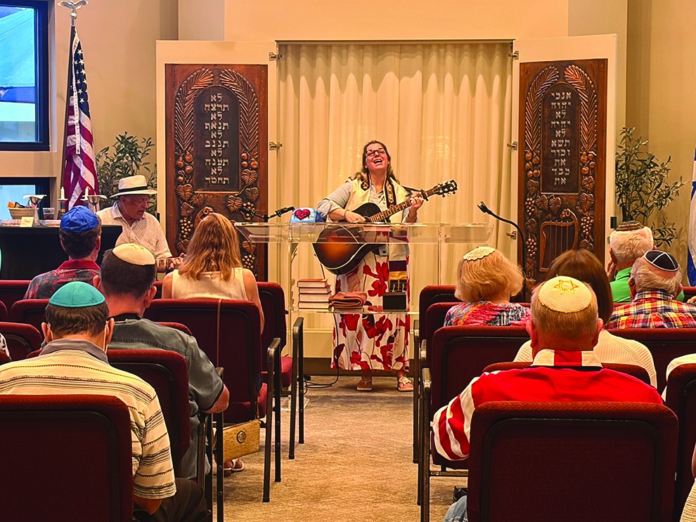 Rabbi Cantor Danielle Bensimhon playing guitar at the Red, White and Blue Shabbat service
