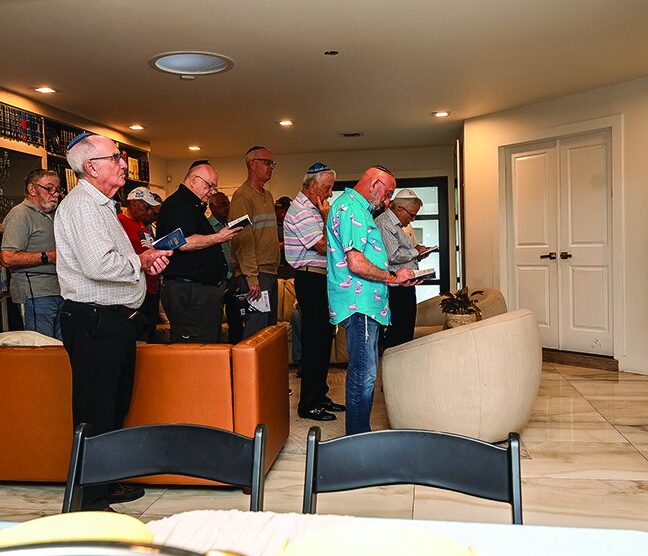 Men standing together in song at Rabbi Vigler’s home farbrengen
