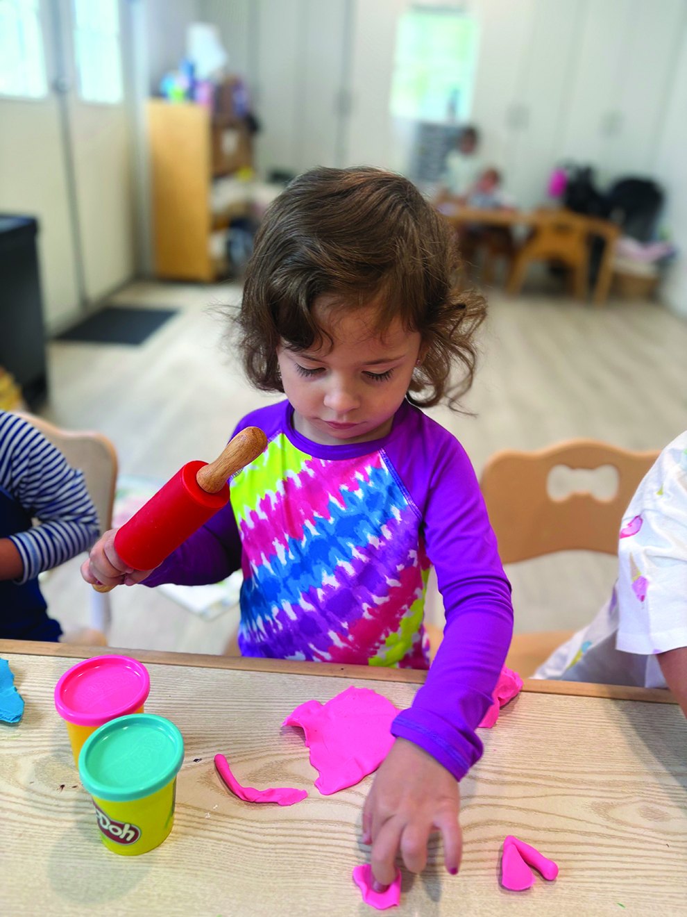 Young camper shaping pink play dough at a Camp Catan craft table