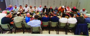 More than 40 men seated at long tables for the Men's Club farbrengen