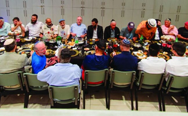 More than 40 men seated at long tables for the Men's Club farbrengen