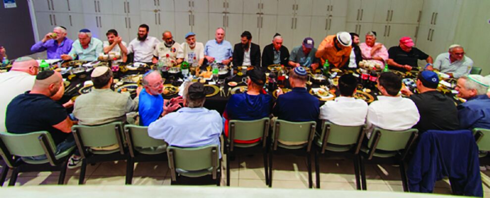 More than 40 men seated at long tables for the Men's Club farbrengen